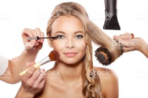 Professional makeup artist and hairdresser are preparing a fashion model.
